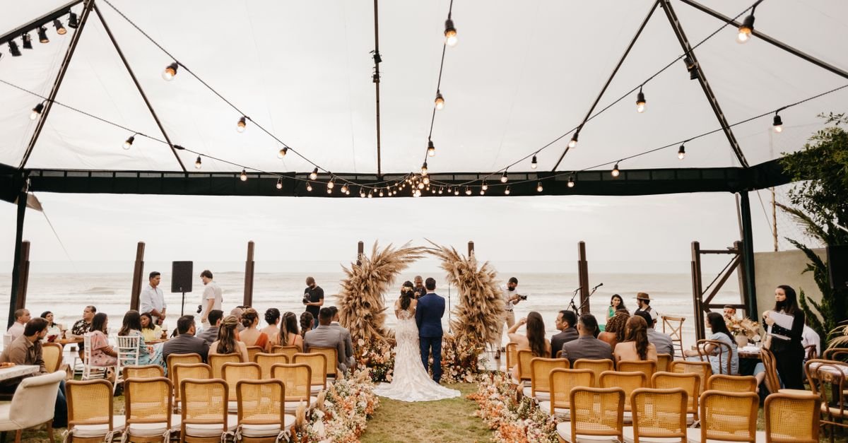 A picturesque wedding ceremony held outdoors under a canopy by the sea. Perfect setting for a romantic event.