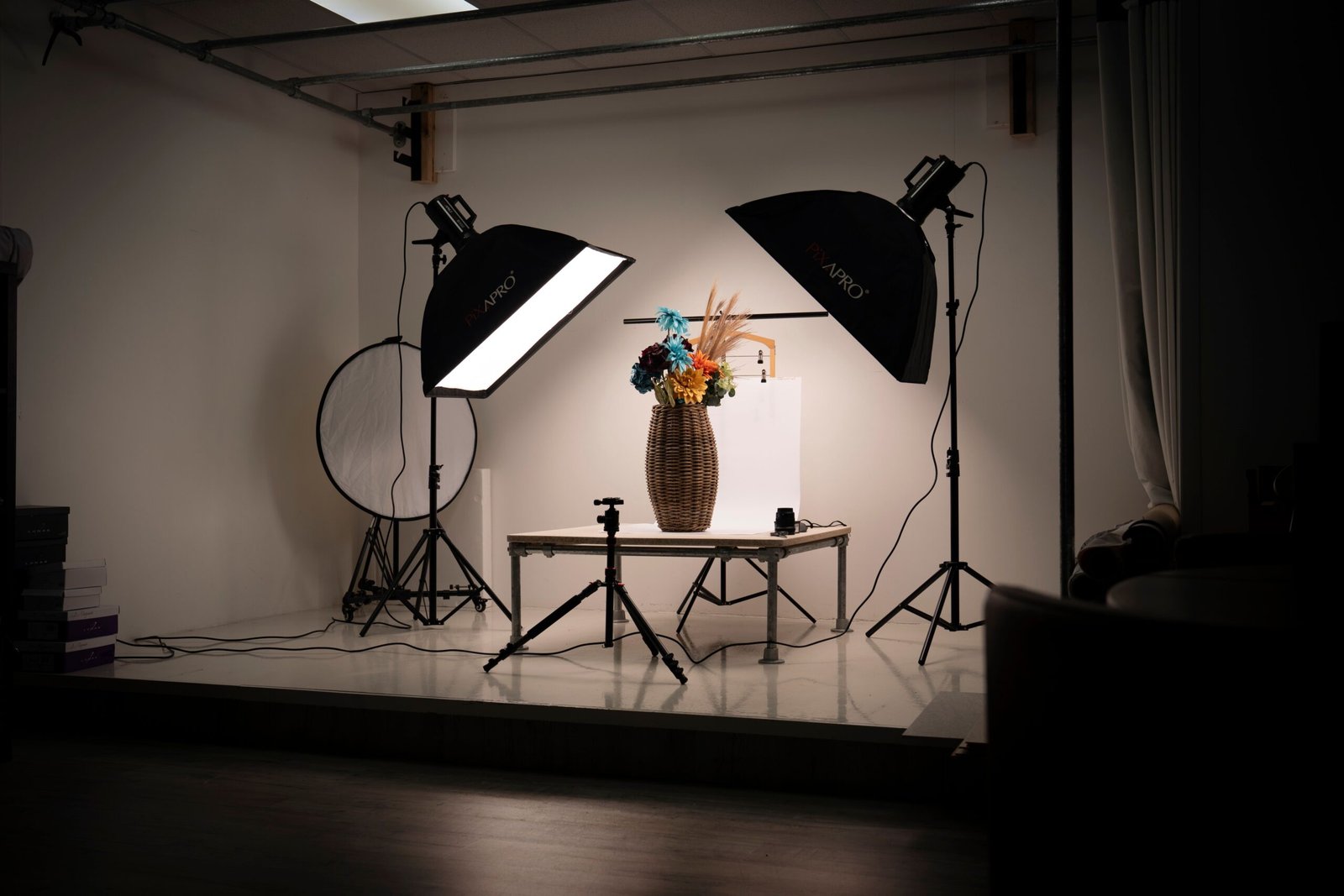 Indoor photography studio setup with lighting equipment and a floral arrangement in a basket. Ideal for studio photography concepts.