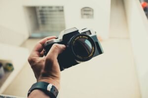From above of crop anonymous male photographer in wristwatch with retro photo camera